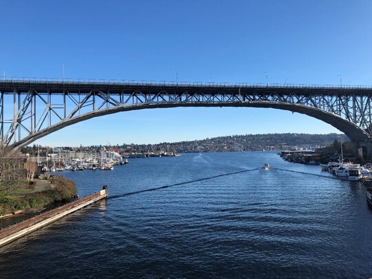A boat goes underneath the Aurora Bridge on a clear-sky day.