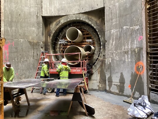 Crews place multiple pipes in a tight space within the recently completed eight-foot diameter tunnel. 