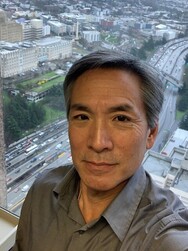 Selfie of Jeff Sakuma in front of his cubicle window in the Seattle Municipal tower