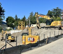 Three different sized dirt excavator vehicles on a construction site
