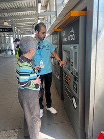 A Hopelink staff member shows a senior how to load money onto an ORCA card