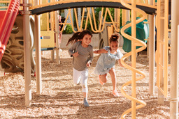 Two children chasing each other through a playground