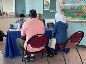 Two OPA staff are sitting at a table at the South Park Community Center helping community members take a survey about Police Accountability
