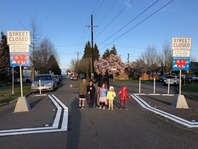 Family smiles between signs and barriers marking a "Healthy Street" closed to through traffic on Beacon Hill