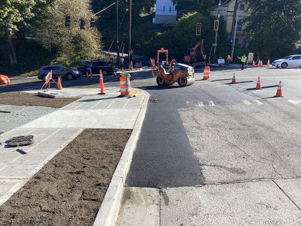 Construction crew member paving the northwest corner of Highland Park Way SW and SW Holden St