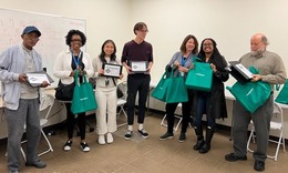 photo of a group of black and white people standing together holding laptops and bags