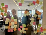 A group of employees putting sticky notes up on a glass wall