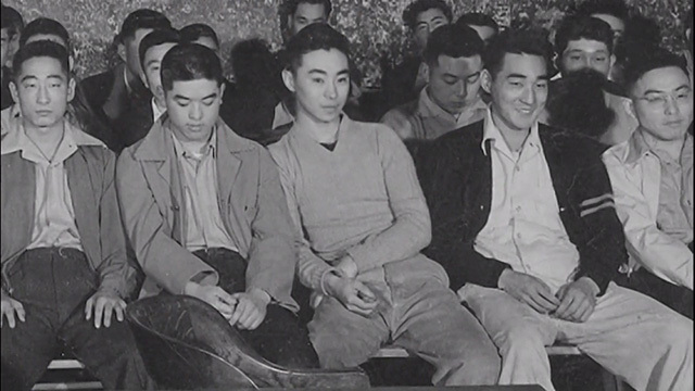 Black and white photo of Japanese American men seated in rows, four rows deep