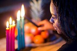 girl lights Kwanzaa candles