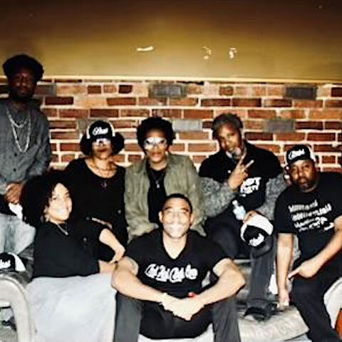 Seven members of Griot Party sit on a couch