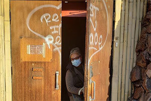 Sakata stands in the old doorway of Bush Garden, "Rest in Peace" spraypainted inside a heart.