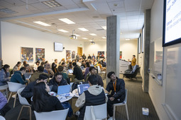 A crowd of hackathon participants listening to instructions