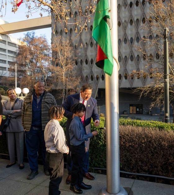 Mayor Harrell and two young boys raise the Black History Month flag