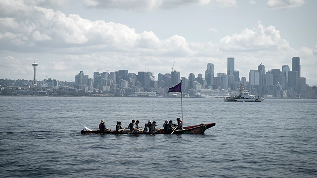 A canoe in the foreground with the Seattle skyline in the distance
