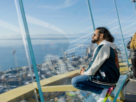 man crouching and looking out window at space needle
