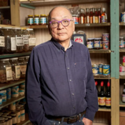 Shopkeeper standing in front his wares.