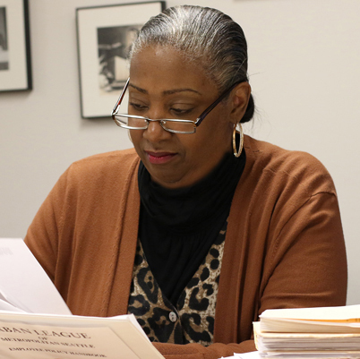 A Black woman sitting a desk reading through papers