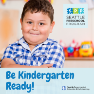 A preschool-aged child wearing a blue and white checkered shirt smiles confidently with arms folded across their chest