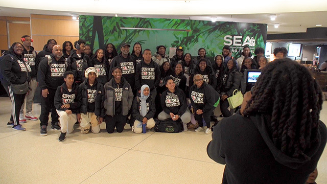 Group of Black high school students and a few adults pose for photo in Seattle-Tacoma Airport