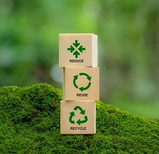 Blocks that say reduce, reuse, recycle on a mossy rock