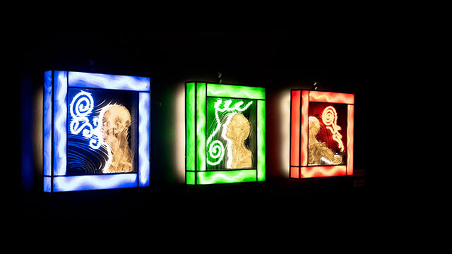 Three neon art panels, (left to right) blue, green, and red with human silhouette