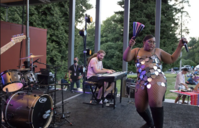 A performer dances on a stage with a band backing them at Trans Pride 2023
