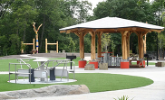 View of a park with accessible paved pathways, a pavilion, and merry-go-round