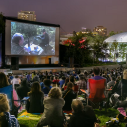 people sitting on lawn chairs watching movie on mural by space needle
