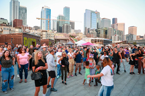 A large group of people at the waterfront block party with Downtown in the background