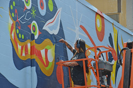 a woman painting a mural in Downtown