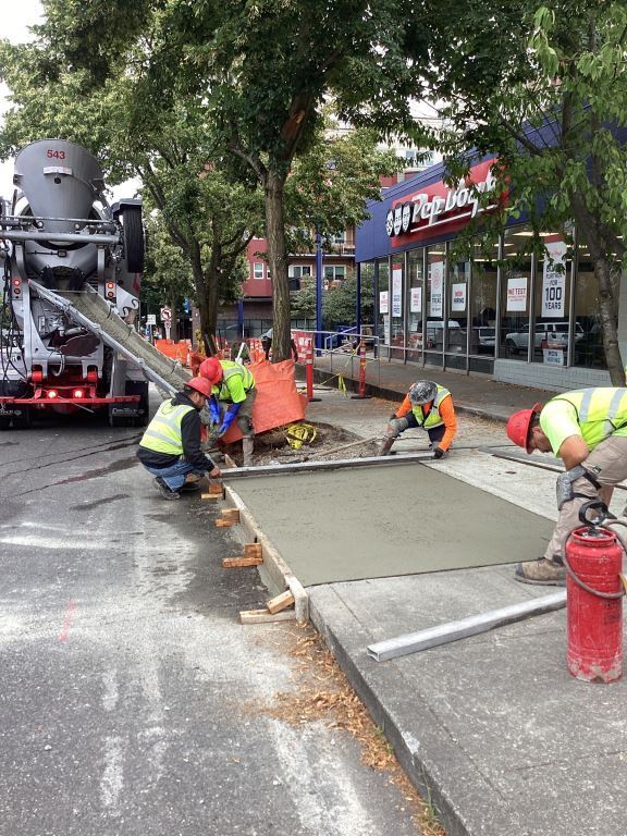 Crews pour new concrete to repair the sidewalk on the west side of 15th Ave NW just south of NW 57th St 