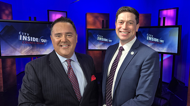 Brian Callanan and Councilmember Dan Strauss in dark blazer smile, stand side-by-side in studio with blue and red background