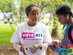 A volunteer in a 411.org tee shirt speaks with a community member