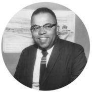 A black and white photo of a man with glasses and a suit and tie