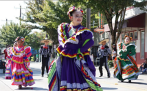 Performers in colorful attire dancing in a street parade