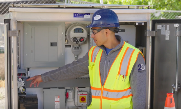 An equipment representative demonstrating features of a roadside electrical cabinet in East Ballard for a training session for SPU workers