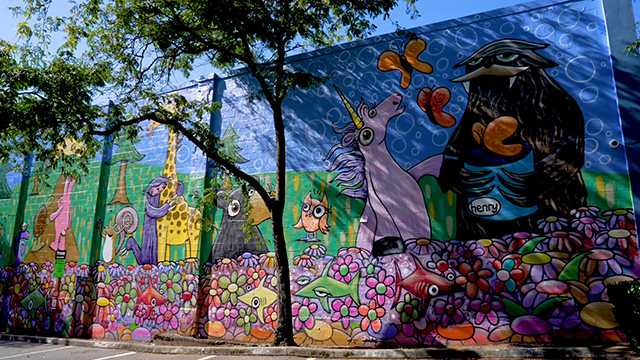 Multicolored mural on side of building featuring various plants and animals