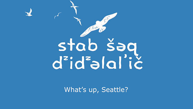 Blue background with white birds, text reads "what's up Seattle" in English and Lushootseed