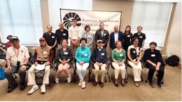  A group of people of varying ages posing indoors in front of a banner that reads National Asian Pacific Center on Aging. 