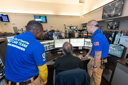 2 CARE community crisis responders and 1 9-1-1 dispatcher looking at dispatchers computer monitors