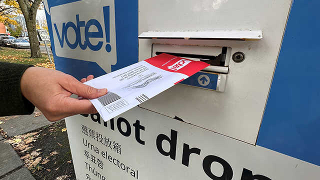 A voter returns a ballot in a ballot box