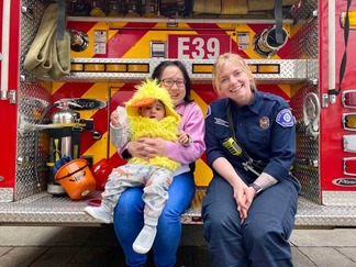 A mother and her child along with a female Seattle firefighter sit on the back of Fire Engine 39.