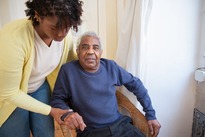 Photo of young Black woman helping an older Black man get up from a chair in photo from pexels.com by Kampus Production #7551667