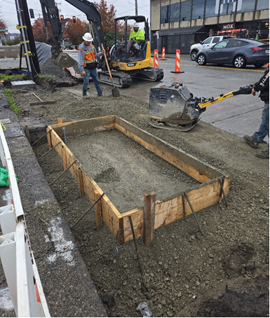 Construction crews work on a new bus stop shelter on NW Ione Place.