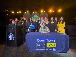 a group of people surround mayor harrell before he signs the music venue loading zone bill