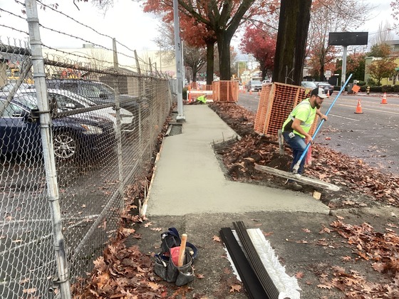 Crews pouring concrete to pave new sidewalk on west side of Rainier Ave S and S College St.