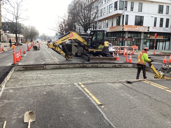 Crews excavated across Rainier Ave S at S Grand St to install underground conduits and preparing for concrete pour.