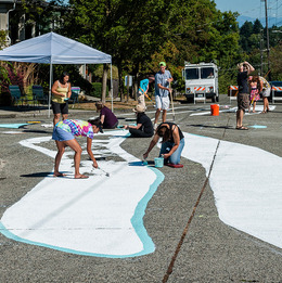 A group of people painting a large mural in an intersection