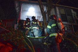 Firefighters carrying a hose line as they prepare to make entry into a burning vacant building in the 100 block of 12th Avenue.