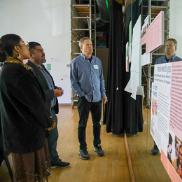 Three people standing by a mirrored wall looking at informational material